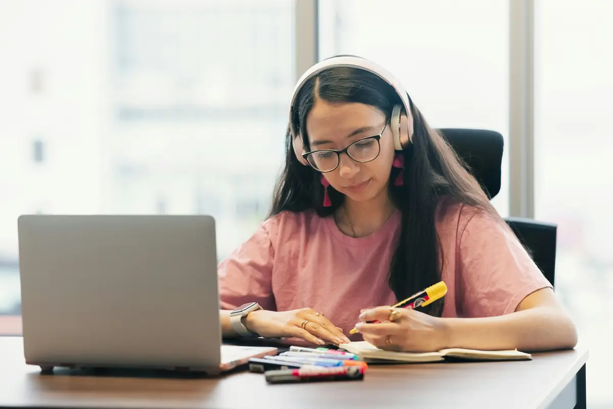 Young woman with headphones studying an online course at her desk